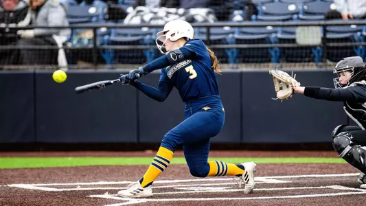 softball player swings and hits the ball at the plate