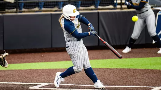 Softball player at the plate hitting a pitch