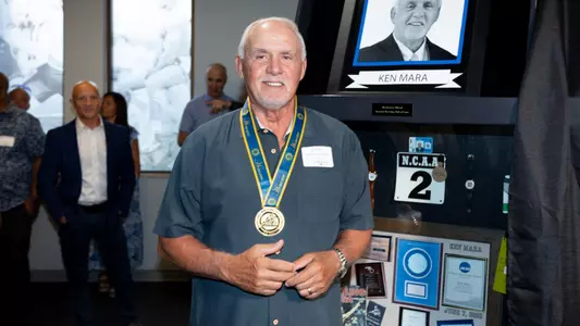 Ken Mara smiles in front of his display at the National Wrestling Hall of Fame & Museum