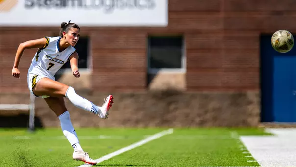 A soccer player in white is kicking the ball.