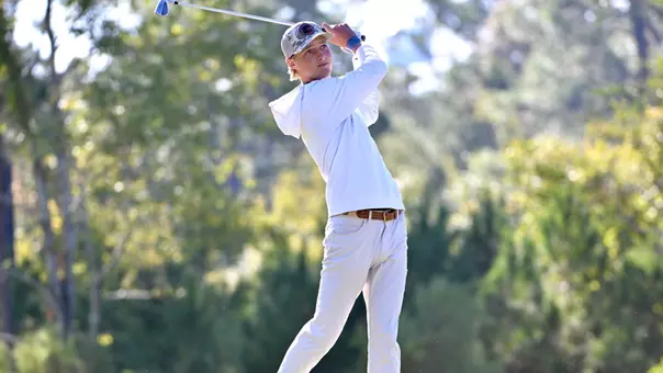 Evan Rogers holds his finish tracking his tee shot with an iron in hand