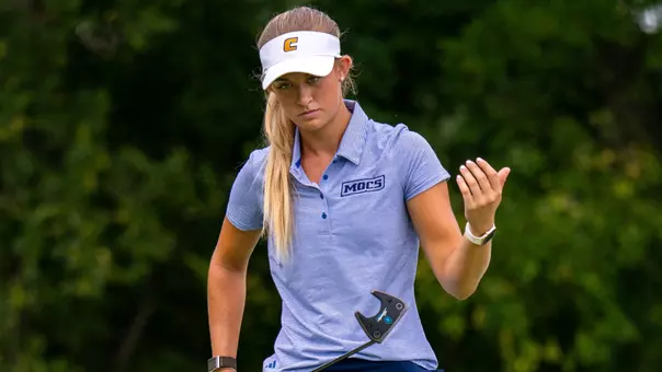 Maggie Carlson eyes her line on the green as she approaches her ball holding her putter in front of her