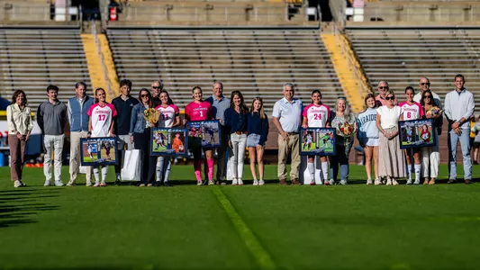 Soccer players in pink and white are with their families on the pitch before the game being honored.