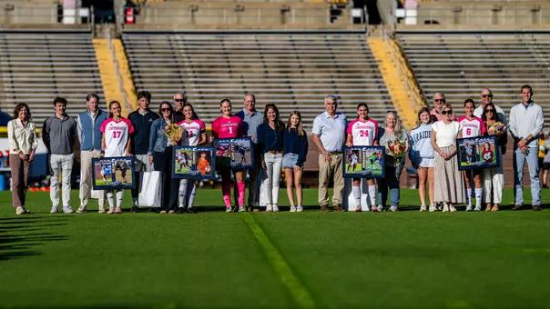 Soccer players in pink and white are with their families on the pitch before the game being honored.