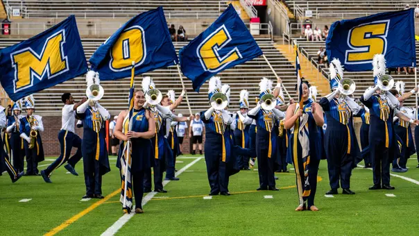 The Marching Mocs are on the field pregame with spirit squads running behind with 4 flags spelling out "Mocs"