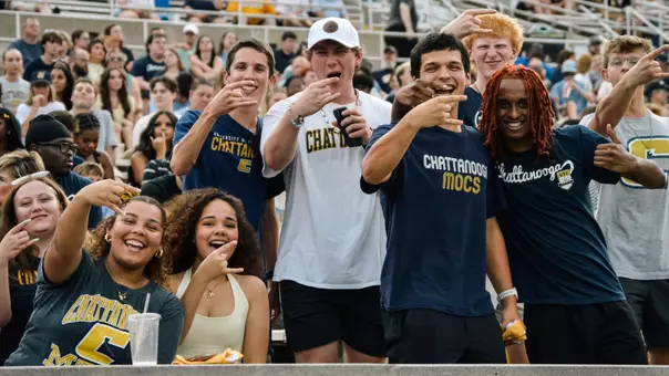 Students stand and flash the Power C hand sign to mug for the camera at Finley Stadium