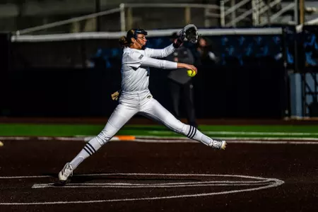 A softball player in the circle throwing a pitch.