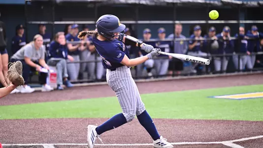 Softball player at the plate hitting the ball.