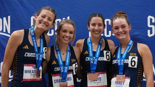 four members of the women's indoor track team displaying their all-conference medals