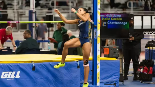 A woman competing in the high jump at the start of her leap.