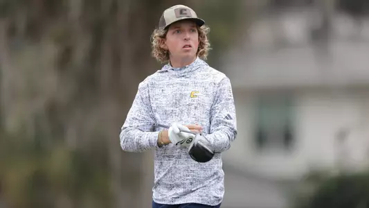 Camden Braidech tucks his driver under his right arm as he looks at his ball in the fairway in the distance