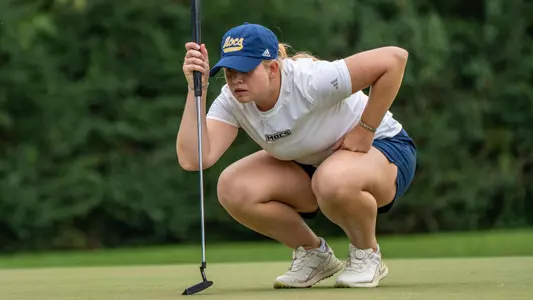 Kera Healey is crouched down reading the green at Vandy in preparation for her birdie effort