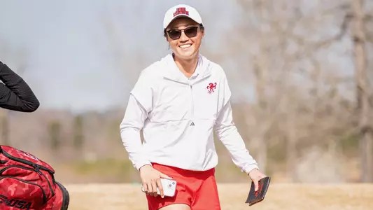 Shelley Chen flashes a big smile walking with her yardage book in hand at Jacksonville State.