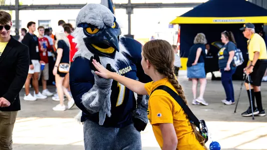 Scrappy and a young Mocs fan high five at football tailgating