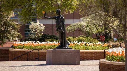 The Torchbearer Statue stands tall as spring flowers bloom in