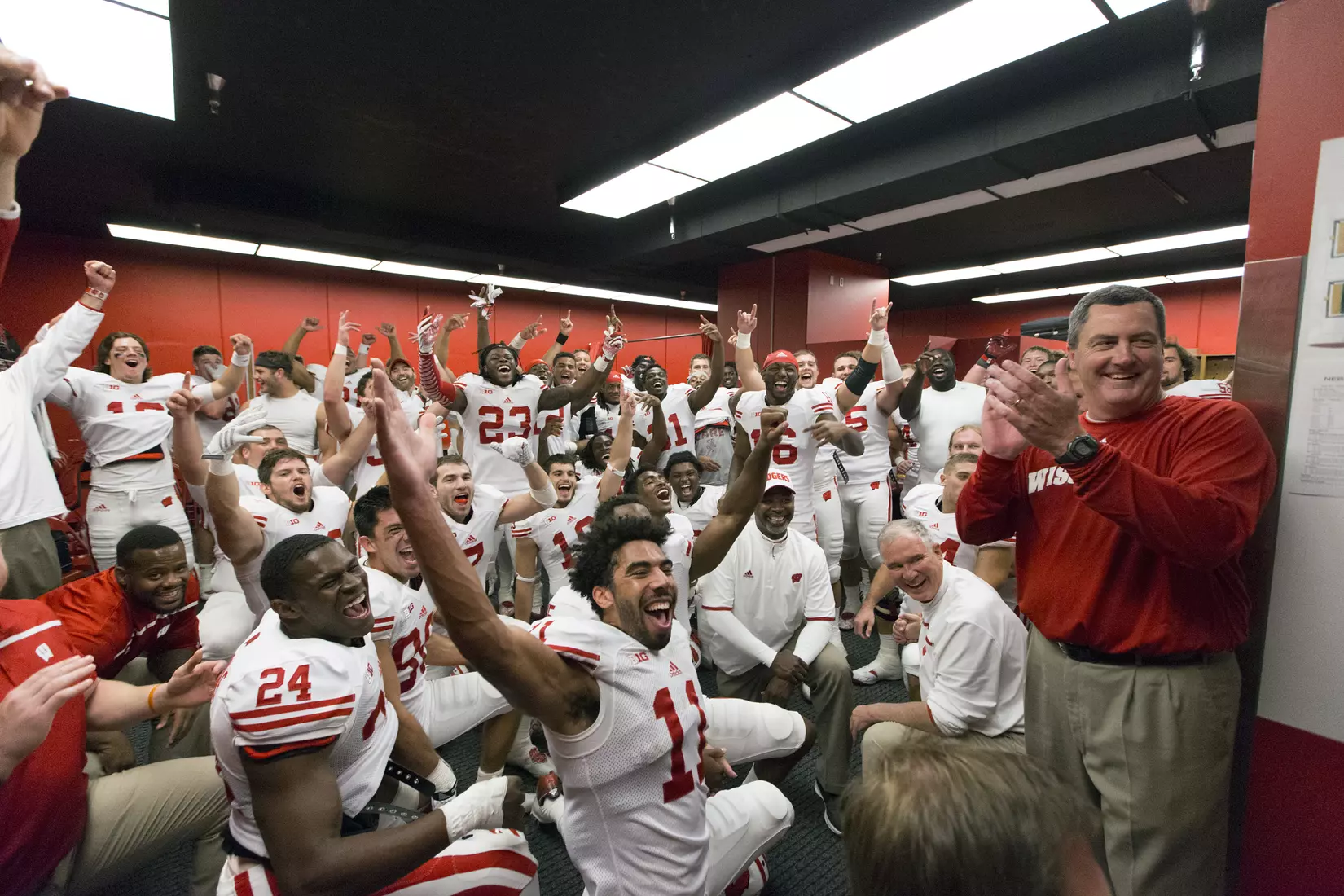 Monsignor Michael Burke ("Father Mike", kneeling on floor near head coach Paul Chryst) with the Wisconsin Badgers football team in the locker room during an NCAA Big Ten Conference college football game against the Nebraska Cornhuskers Saturday, October 3, 2015, in Lincoln, Neb. The Badgers won 23-21. (Photo by David Stluka)