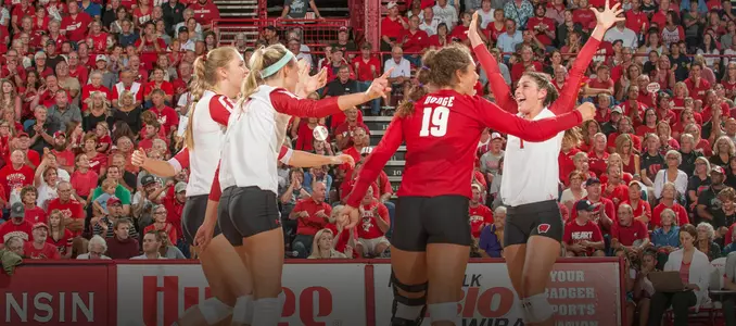 The Badger volleyball team celebrates on the court.