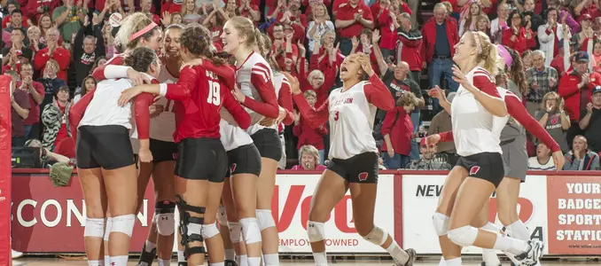 The Badger volleyball team celebrates on the court.