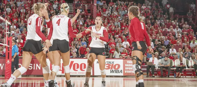 The Badger volleyball team celebrates on the court.