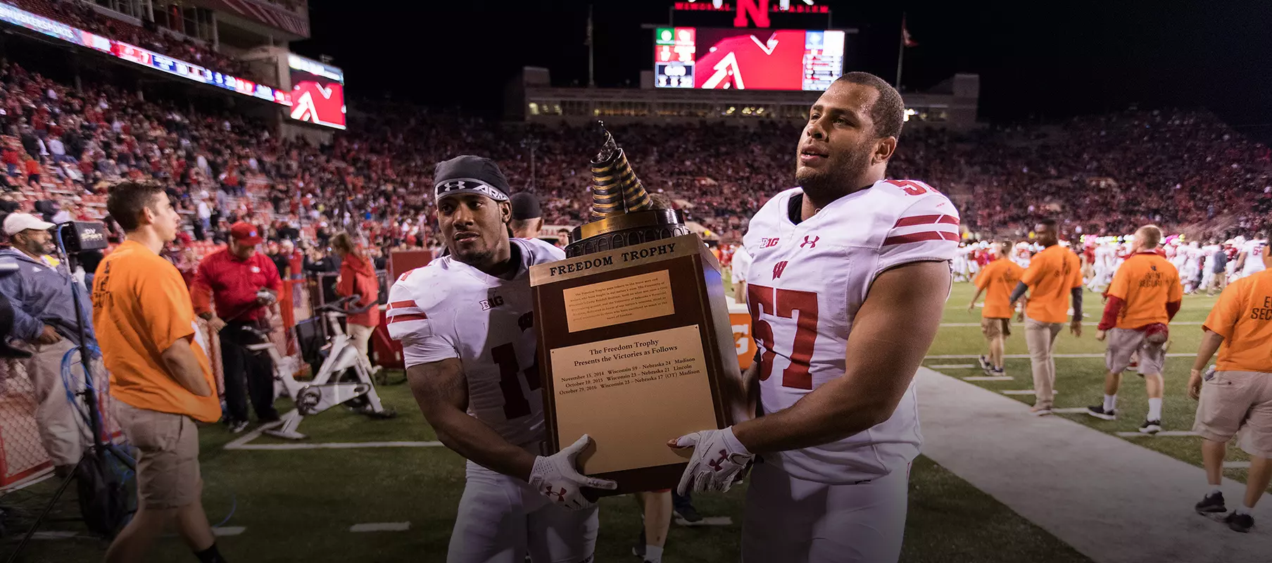 Photo of D'Cota Dixon, T.J. Edwards carrying Freedom trophy after football defeated Nebraska 2017