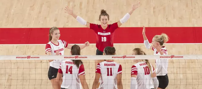 The Badger volleyball team celebrates on the floor