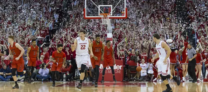 Photo of Ethan Happ running down the court during a men's basketball game as the student section throws newspaper confetti vs. Maryland 2017