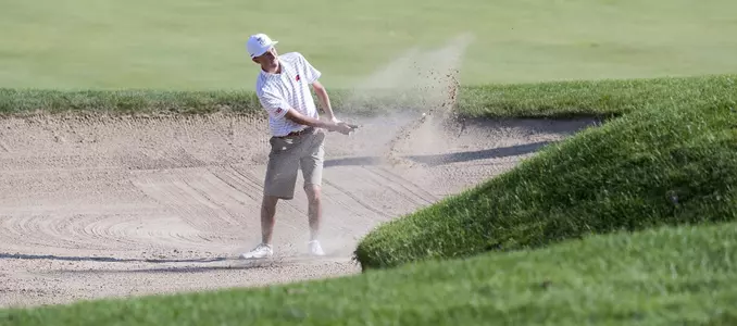 Photo of freshman Griffin Barela hitting out of a sand trap on the ninth hole during the 2017 Badger Invitational at University Ridge Golf Course