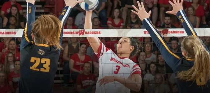 Lauryn Gillis attacks the ball between two Michigan blockers.