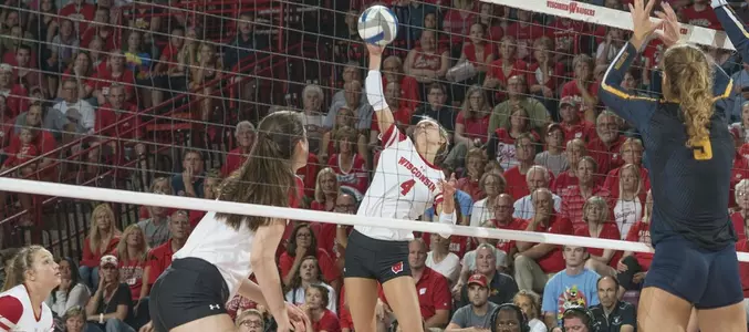 Kelli Bates attacks the volleyball against two Marquette blockers.