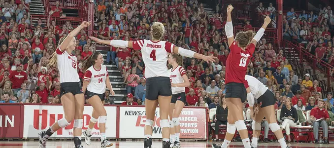 The Badger volleyball team celebrates winning a point by gathering on the court.