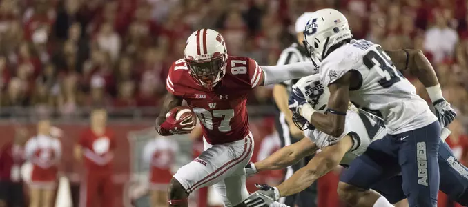 Photo of Quintez Cephus carrying the ball and fending an opponent during football game vs. Utah State 2017