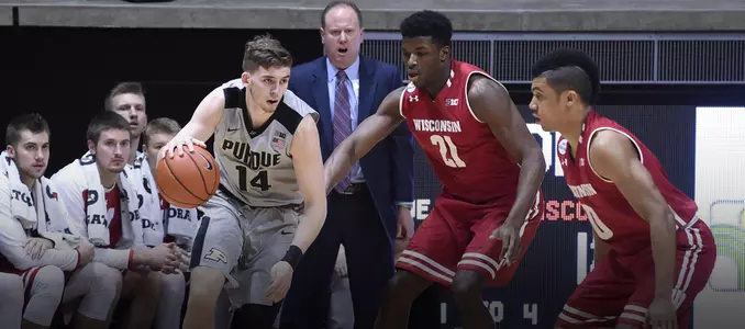 Ryan Cline dribbles the basketball with Khalil Iverson and D'Mitrik Trice defending him during a game between Wisconsin and Purdue