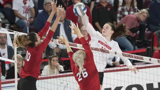 Dana Rettke attacks the ball against two Nebraska blockers.