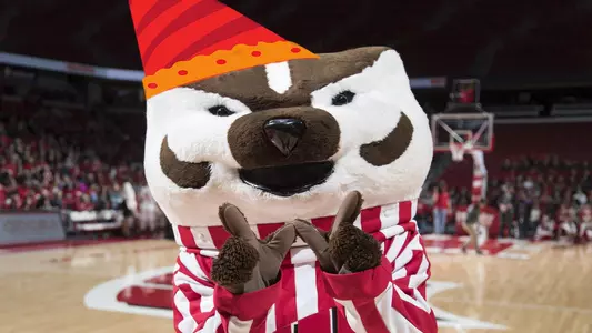 Bucky Badger at a women's basketball game with a birthday hat.