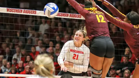 Grace Loberg hits a ball past two Minnesota blockers.