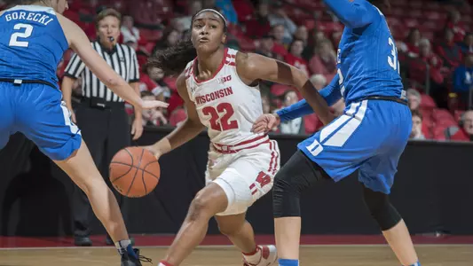 Niya Beverley dribbles between two Duke defenders.