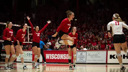 The Badgers celebrate on the floor during a match.