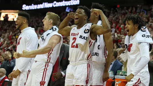 Men's basketball players Charlie Thomas, Brevin Pritzl, Khalil Iverson, Aleem Ford, and Tai Strickland on the bench at the Kohl Center cheering