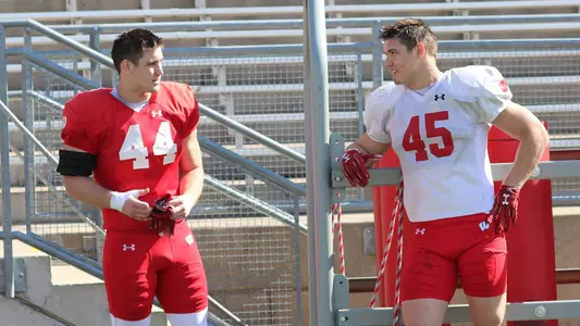 John Chenal (44) and Leo Chenal (45) talk at football spring practice inside Camp Randall Stadium
