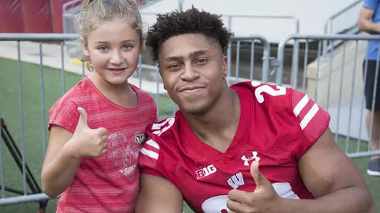 Wisconsin football running back Jonathan Taylor (23) gives a thumbs up with a young fan at the 2018 Family Fun Day inside Camp Randall Stadium.