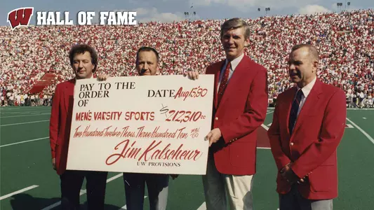 Jim Klascheur (2nd from left) presents a check to Pat Richter and Duane Kleven at a Wisconsin football game in 1990 with UW Hall of Fame text.
