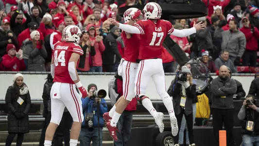 Jack Coan jumps in the air to celebrate with a UW teammate