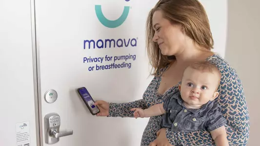 A Mom and Baby use an app on their cell phone to enter the Mamava Lactation Pod