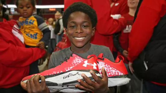 Wisconsin Shoe Project - a young boy holds a shoe given to him by Ethan Happ