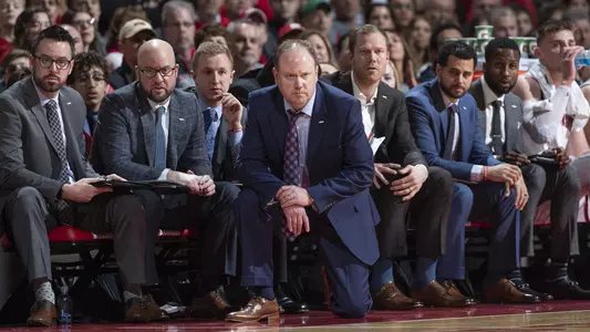 Wisconsin Badgers head coach Greg Gard kneels in front of his staff during an NCAA Big Ten Conference college basketball game against the Minnesota Golden Gophers, Sunday March 1, 2020, in Madison, Wis. The Badgers won 71-69. (Photo by David Stluka/Wisconsin Athletic Communications)