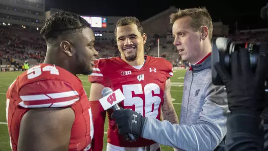 Wisconsin Badgers reporter Chris Hall, left, interviews linebacker Chris Orr (54) and Zack Baun (56) after an NCAA college football game against the Purdue Boilermakers Saturday, Nov. 23, 2019, in Madison, Wis. The Badgers won 45-24. (Photo by David Stluka/Wisconsin Athletic Communications)