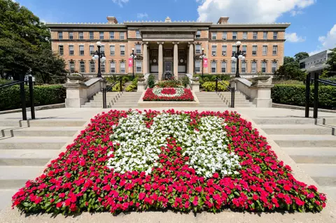 Contrasting red and white flowers form the letters U and W in flowerbeds leading to the entrance of Agricultural Hall at the University of Wisconsin-Madison during summer on Aug. 9, 2017. (Photo by Jeff Miller / UW-Madison)