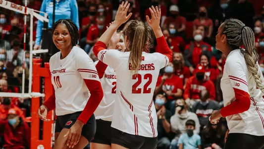 The Badgers slap hands on the court in celebration.