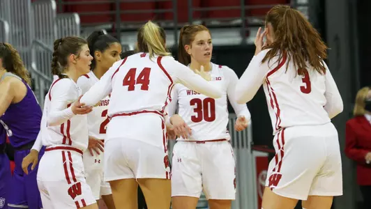 Five Badgers huddle up on the floor.