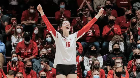 Dana Rettke celebrates with her arms raised on the sidelines.